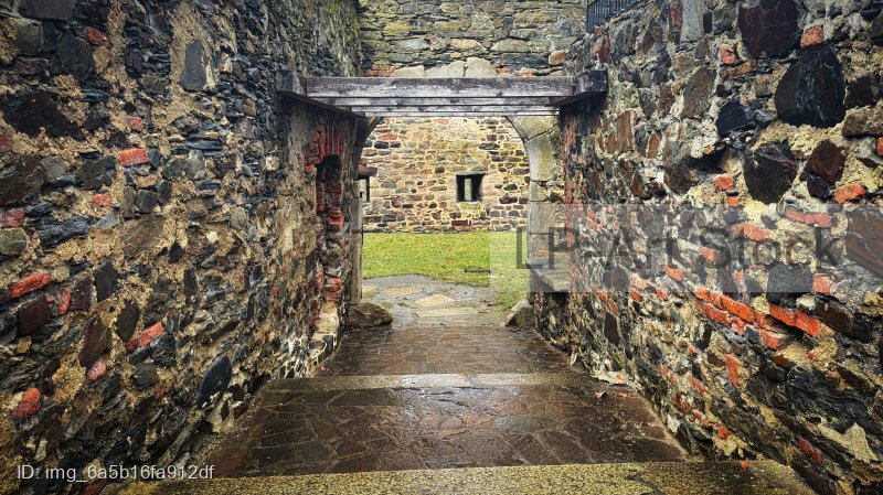 Gepflasterter Durchgang zwischen historischen Steinmauern